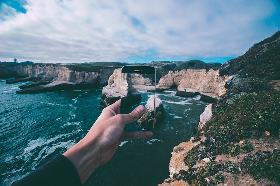 Man Holds Smart Phone to Photograph Coastline Map App